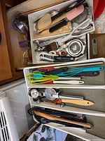 Drawer organizers filled with assorted utensils including spatulas, whisks, spoons, pizza cutter, ice-cream scoop, garlic press, measuring spoons