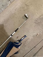 Golf putter and fabric umbrella on concrete floor