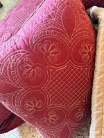 Close-up of quilted burgundy decorative pillow showing embroidery