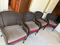 Four wicker/rattan armchairs lined up with cushions in place