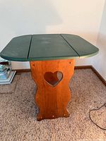 Front view of table showing green top, heart cut-out, lower shelf