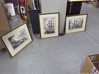 Three framed maritime prints leaning on floor