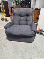 Front view of dark gray upholstered armchair with tufted back and padded arms