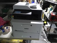Front three-quarter view showing touchscreen, scanner lid, paper tray and Brother logo