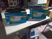 Two unopened-looking Ecosmart LED BR30 65W bright white bulb boxes on table