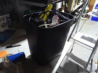 Overall view of black plastic bin filled with electric hair styling devices