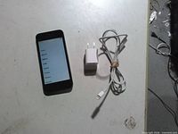 Front view of iPhone showing setup screen alongside charger and cable
