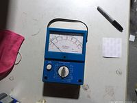 Front view of Simpson analog multimeter showing meter scale, selector knobs, strap