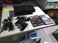 Console, cords, controller, two games laid out on table