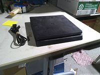 Top view of PlayStation 4 Slim with power cord on table