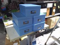 Stack of five blue storage boxes with metal handles