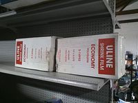 Two white cartons labeled Uline Shrink Film Economy Polyolefin on metal shelf