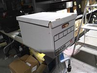 Closed cardboard file box holding the VHS tapes