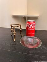 Stand and glass dish beside soda can for scale