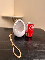 Front view showing opening and jute rope beside soda can for scale