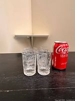 Four etched tumblers beside soda can for scale