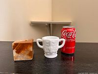 Front view of sugar bowl beside stone candleholder and Coke can for scale