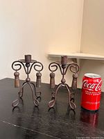 Front view of both metal candlestick holders beside soda can for scale