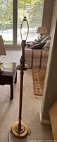 Full view of brass and wood floor lamp standing in room
