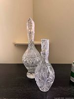 Front view of both decanters showing size difference and cut patterns
