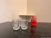Front view of three etched cornflower tumblers beside soda can for scale