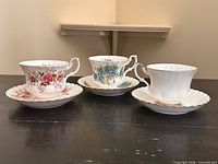 Three Royal Albert teacup and saucer pairs on table showing fronts