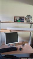Overall view of desk, monitor, keyboard, mouse and shelf contents