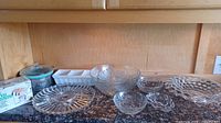 All eight clear glass serveware pieces arranged on countertop