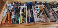 Drawer with trays showing full assortment of office supplies, batteries, tools and tapes