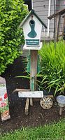 Birdhouse on post with surrounding smaller accents and one solar light