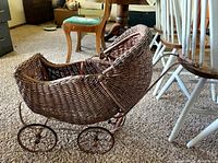 Side view of wicker doll carriage showing body, wheels and handle