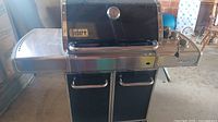 Front view of Weber Genesis propane grill with side shelves and cabinet doors