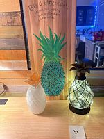 Wood sign, ceramic pineapple, glass lamp on tabletop