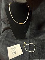 Necklace displayed on bust and bracelet laid flat showing entire set
