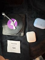 Apple AirPods case, blue earbuds case, vinyl record on small turntable base