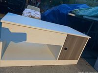 Front view of coffee table showing white finish, oak-tone cabinet door, open shelf