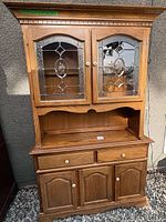 Full front view of oak hutch showing upper glass doors, open shelf, lower drawers and doors