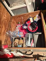 Overview of chest with assorted disposable cups, bowls, utensils, burlap-wrapped jars