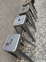 Row of five metal bar stools showing tops and legs