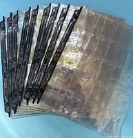 Stack of ten clear 2"x2" coin pages showing pockets and black three-hole edge