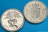Both £1 coins showing reverse designs: leek in coronet and crowned Royal Arms