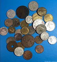 Overview of approx. 28 assorted world coins on blue background
