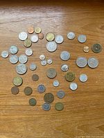 Overhead view showing entire assortment of world coins spread on wooden surface