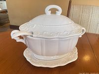 Tureen with lid, ladle resting in notch, on underplate