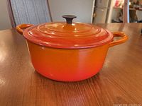 side view of orange enameled casserole with lid