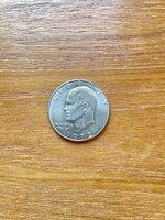 Obverse of 1972 Eisenhower dollar coin on wood surface