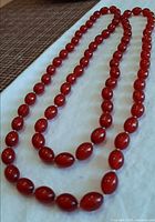 Full view of long red amber bead necklace laid out