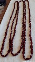 Three cherry amber necklaces laid out to show length and bead shape