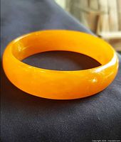 Full view of orange Bakelite bangle bracelet showing color and shape