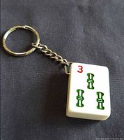Front view of white bakelite mahjong tile keychain showing red 3 and green bamboo symbols